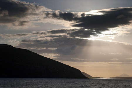Sunrays breaking through the clouds over the sea and islandsの写真素材
