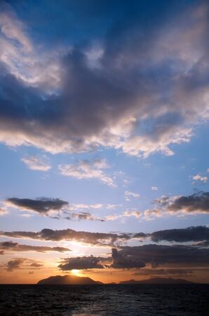 Sunrays breaking through the clouds over the sea and islandsの写真素材