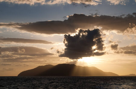 Sunrays breaking through the clouds over the sea and islandsの写真素材