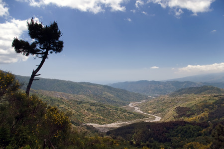 Beautiful valley of the sicilian hinterland under the majestic volcano Etna with dry river bedの写真素材