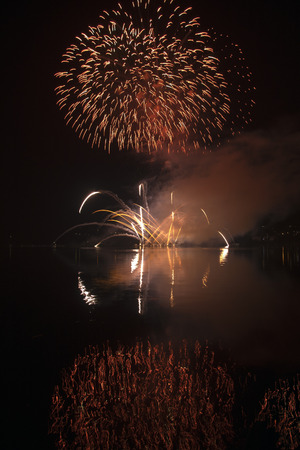 Colorful fireworks on the black sky background and water reflectionsの写真素材