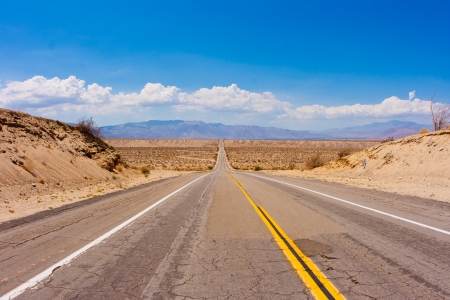 Big dip in the road along a desert highway  Clouds and mountains in the background の写真素材