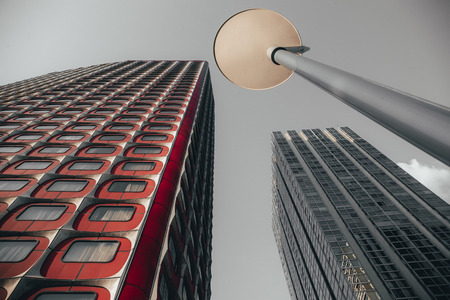 Detail of modern skyscrapers, one with red accents and a street lamp in Beaugrenelle, Paris France viewed looking up from belowの写真素材