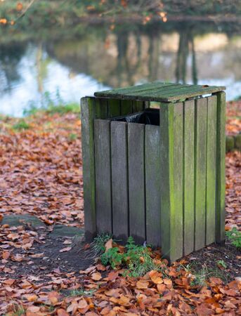 A wooden park bing covered in green and surrounded by golden autumn leaves.の写真素材