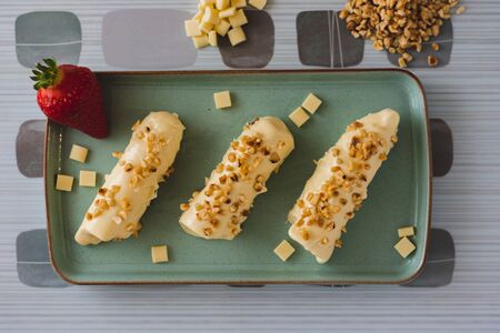 White chocolate covered meringue bars with nutes on top sitting on a blue plate