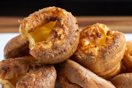 A close up of the top most Yorkshire pudding sitting on a stack over other puddings