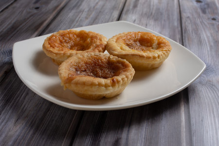 Three traditional bakewell puddings sitting on a white plate viewed from the side