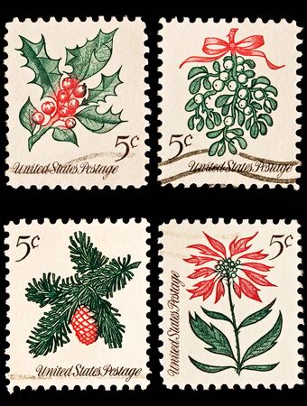 A variety of four Christmas postage stamps. Sprig of conifer, poinsettia, mistletoe and hollyの写真素材