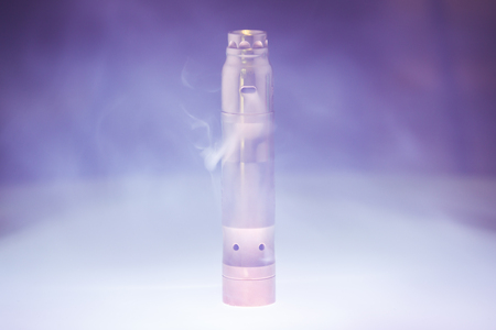 Electronic cigarette with steam in smoke on a dark background. Alternative to smokingの写真素材