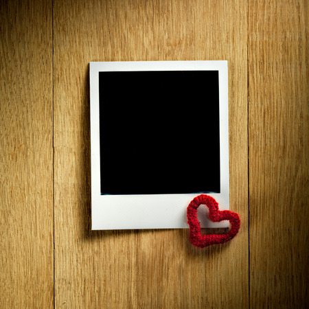 Polaroid fiilm vintage empty photo card decorated with a tiny heart on wooden backgroundの写真素材