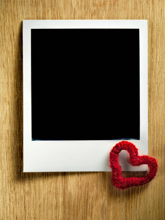 Polaroid fiilm vintage empty photo card decorated with a tiny heart on wooden backgroundの写真素材