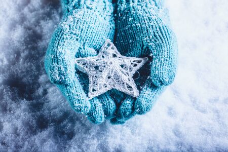 Female hands in light teal knitted mittens with entwined white star.の写真素材