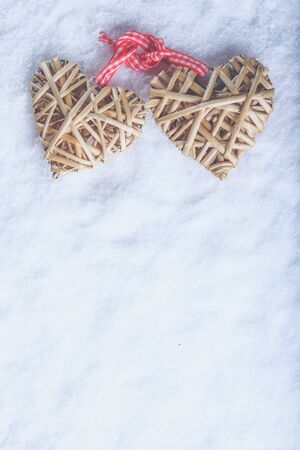 Two vintage entwined beige flaxen hearts tied together with a ribbon on white snow.の写真素材