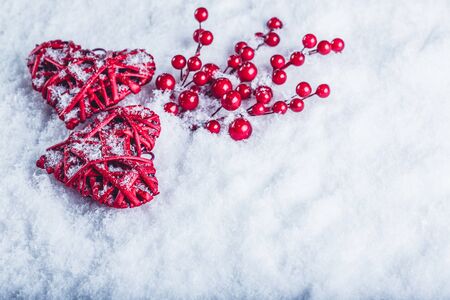 Two red hearts with mistletoe berries on a white snow winter background.の写真素材