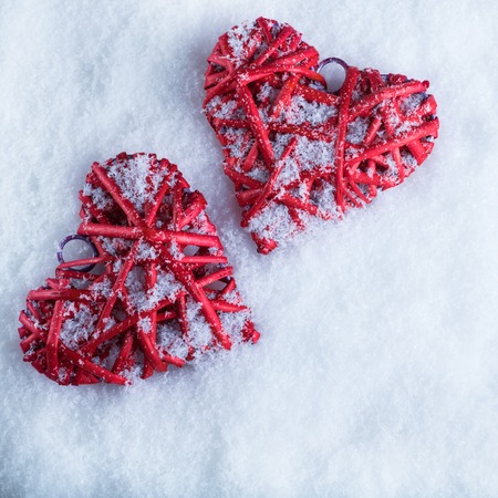 Two beautiful romantic vintage red hearts together on a white snow winter background.の写真素材