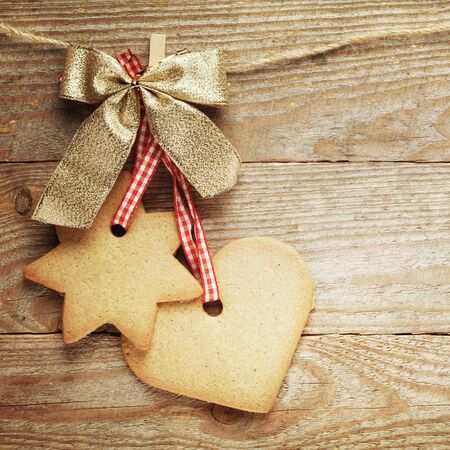 Gingerbread cookies and christmas decorations hanging over wooden background.の写真素材