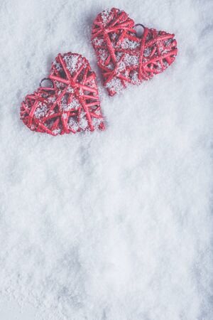 Two beautiful romantic vintage red hearts together on a white snow winter background.の写真素材