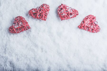 Four red hearts on a white snow winter background.の写真素材