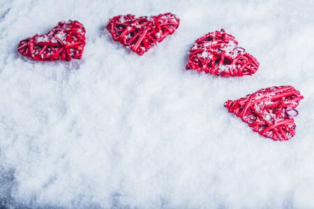 Four red hearts on a white snow winter background.の写真素材