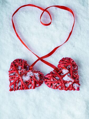 Two red hearts tied together on a white snow winter background.の写真素材
