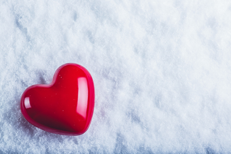 Red glossy heart on a frosty white snow winter background.の写真素材