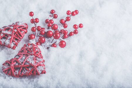 Two red hearts with mistletoe berries on a white snow winter background.の写真素材