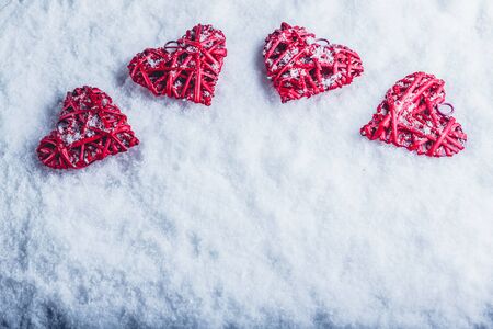 Four red hearts on a white snow winter background.の写真素材
