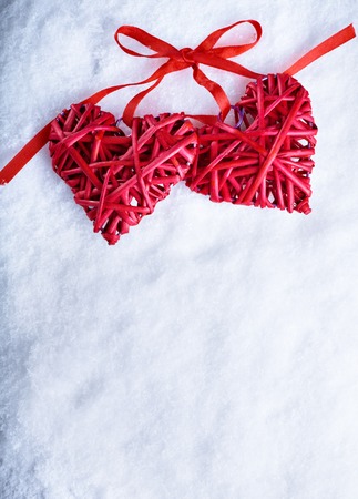 Two beautiful romantic vintage red hearts together on a white snow winter background.の写真素材