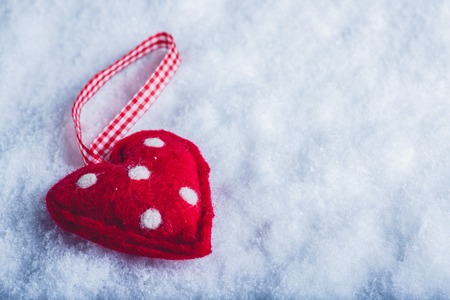Red toy suave heart on a frosty white snow winter background.の写真素材