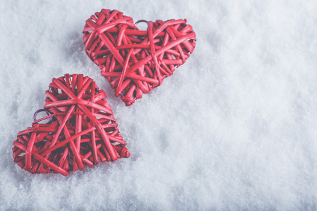 Two beautiful romantic vintage red hearts together on a white snow winter background.の写真素材
