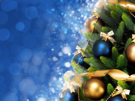 Magically decorated Christmas Tree with balls, ribbons and garlands on a blurred blue shiny and sparkling background.の写真素材