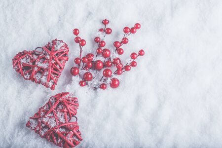 Two beautiful romantic vintage red hearts with mistletoe berries on a white snow winter background.の写真素材