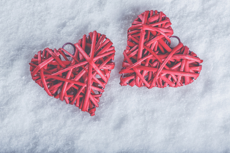 Two beautiful romantic vintage red hearts together on a white snow winter background.の写真素材