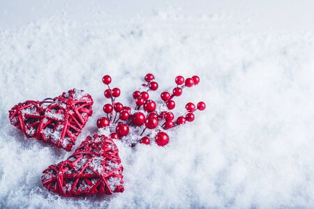 Two red hearts with mistletoe berries on a white snow winter background.の写真素材