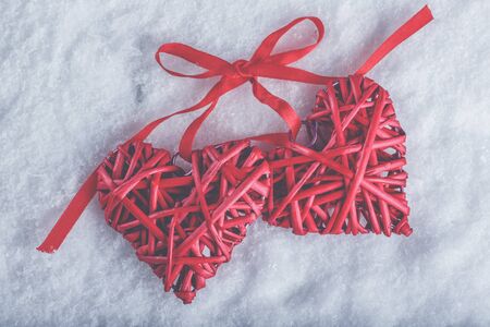 Two red hearts tied together on a white snow winter background.の写真素材