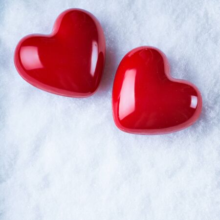 Two red hearts on a white snow winter background.の写真素材