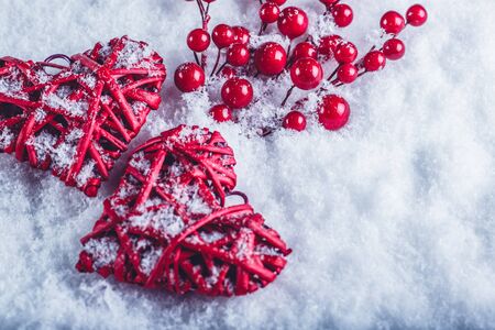 Two red hearts with mistletoe berries on a white snow winter background.の写真素材