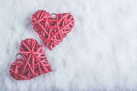 Two beautiful romantic vintage red hearts together on a white snow winter background.の写真素材