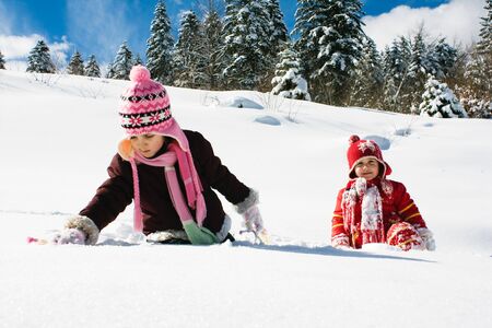 two little girls playing on the snowの写真素材