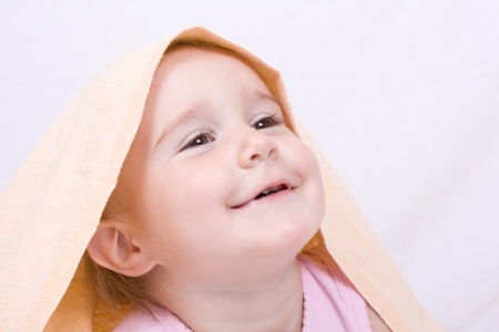 Portrait of the little baby under a terry towelの写真素材