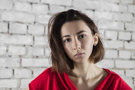 Photo with a serious girl standing against white brick wallの写真素材