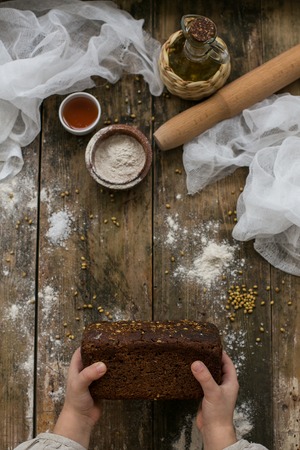 childrens hands cutting wheaten bread on the wooden board, selective focusの写真素材