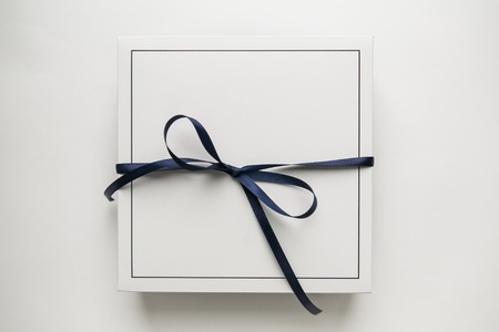 Single white gift paper box with blue ribbon bow, isolated on white backgroundの写真素材