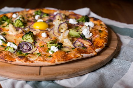 Delicious fresh homemade pizza with onions, vegetables and cheese on a wooden table. Copy space. close-up.の写真素材