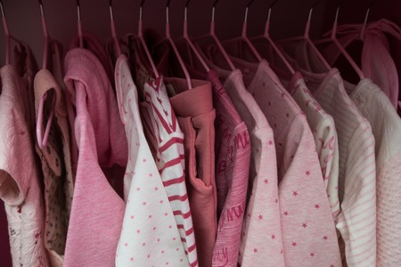 A lot of pink childrens clothes on hangers. Childrens wardrobe with clothesの写真素材