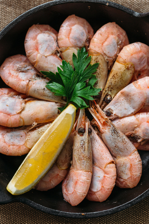 Boiled shrimp with lemon and parsley on a wooden table. Close upの写真素材