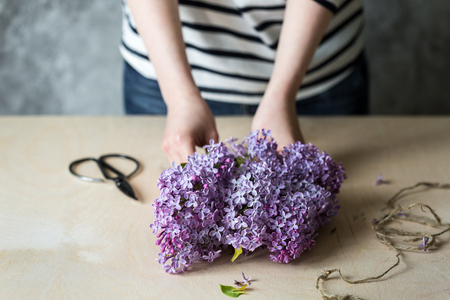 Woman hands making bouquet of lilac in a pot on the tableの写真素材
