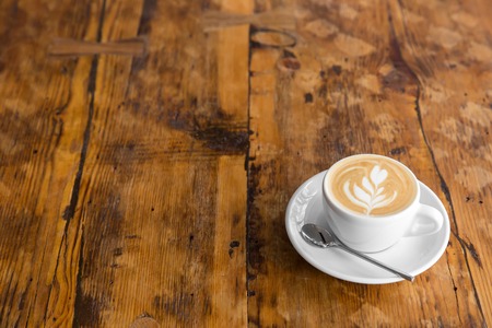 Cup of coffee to go on the wooden table with latte art. Street coffee. copy spaceの写真素材