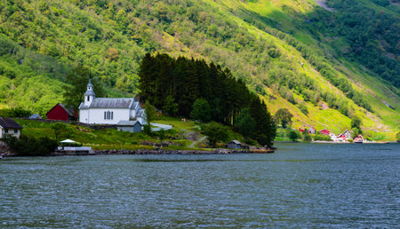Traditional white Christian church in amazing Aurlandsfjord with small wooden housesの写真素材