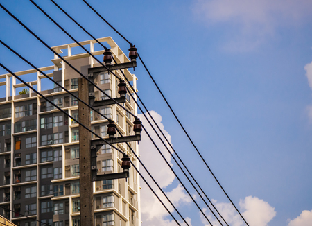 Electric pole,electric cable with building and blue sky backgroundの写真素材